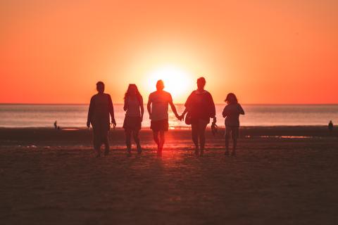group of people walking in front of setting sun